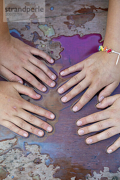 Junge Mädchen mit ihren Händen in Wasserfarben haben Spaß