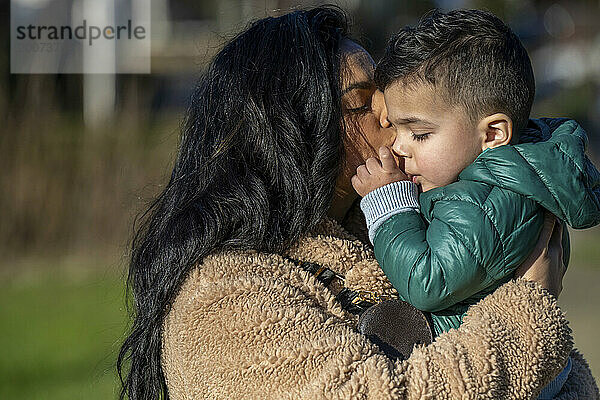 Mutter und Sohn umarmen sich im Park.