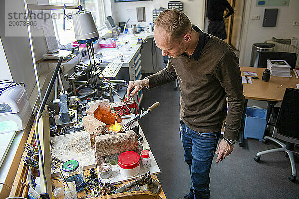 Uhrmacher repariert eine klassische Uhr und Schmuck  authentischer Arbeitsplatz. Verwenden Sie kleine Werkzeuge für Reparaturen  die in einem kleinen Ofen erhitzt werden