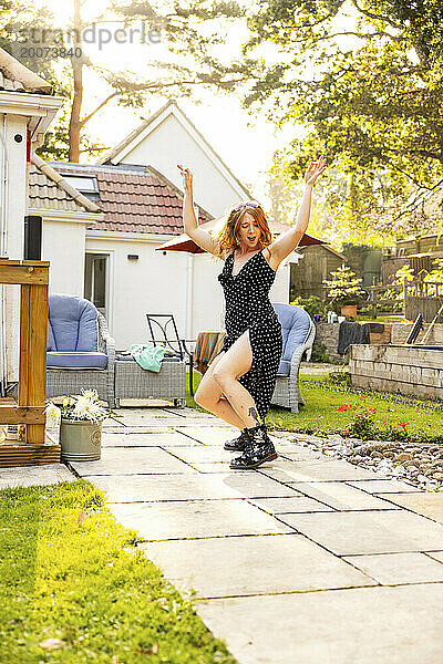 Eine rothaarige junge Frau  die draußen auf einer Sommergartenparty tanzt und Spaß hat