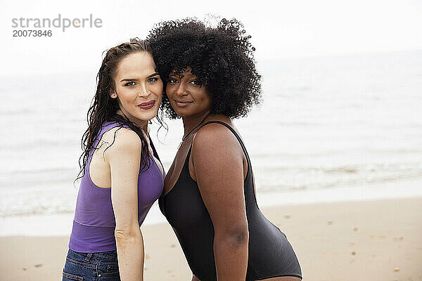 Porträt oder eine junge schwarze Frau und ihre junge Transgender-Freundin posieren am Strand und haben Spaß.
