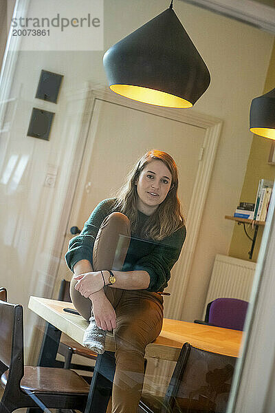 Nederland - Junge Frau sitzt auf der Küchentafel und blickt in die Kamera. Foto: Patricia Rehe / ANP / Hollandse Hoogte