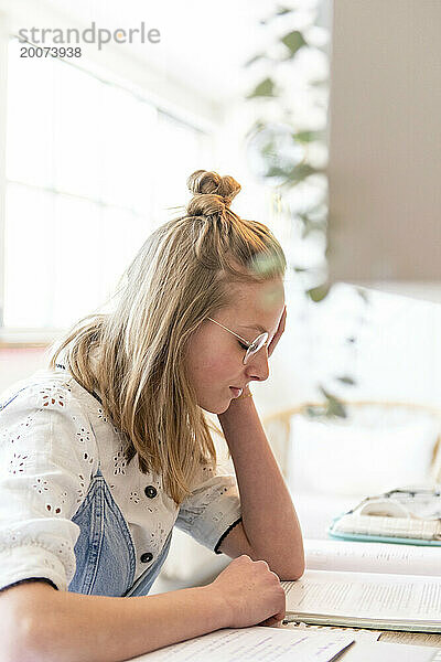 Blonde attraktive junge Frau sitzt an ihrem Schreibtisch in ihrem Zimmer und studiert auf ihrem Laptop. Ich werde frustriert und genervt