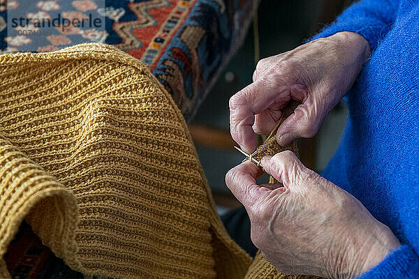 Close up of an Elderley lady knitting at her dining room table