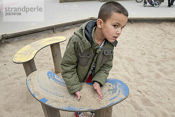 Boy playing with sand in a public park