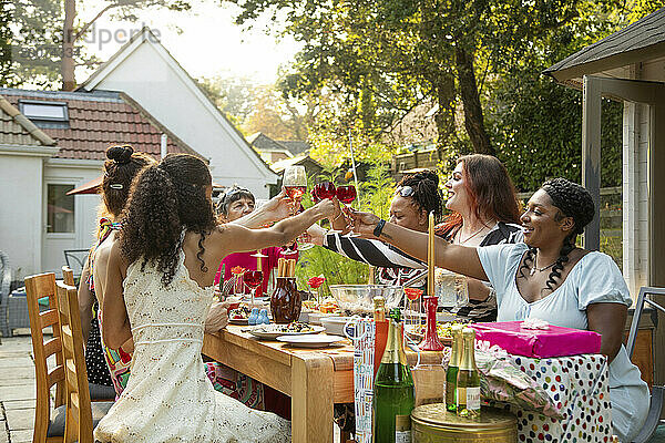 Eine gemischte Zusammenkunft von Frauen  die bei einer Sommergarten-Geburtstagsfeier zum Mittagessen lachen und Spaß haben