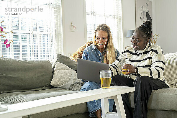 Freunde sitzen zusammen mit ihrem Laptop auf dem Sofa und planen einen Urlaub