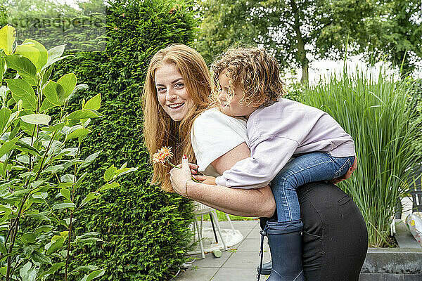 Mutter und Sohn spielen im Garten mit einem Huckepack