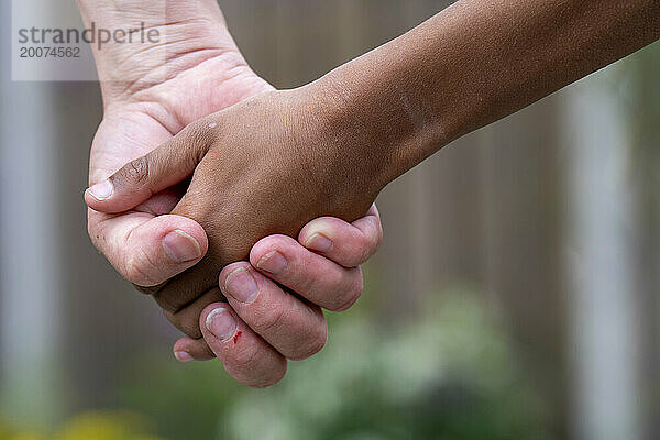 Mutter und Sohn gemischter Abstammung halten Händchen zusammen. Bedingungslose Liebe