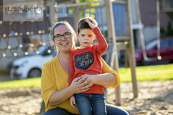 Gleichgeschlechtliche Eltern stehen mit ihrer Tochter und ihrem Sohn im Park für ein Porträt in einem öffentlichen Park. Glücklicher Bonding-Moment mit wunderschönem Sonnenlicht