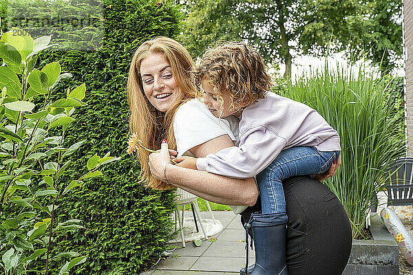 Mutter und Sohn spielen im Garten mit einem Huckepack