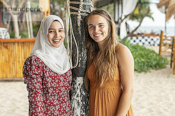 Porträt zweier bester Freundinnen  eine davon trägt einen Hijab in einem Strandresort im Süden Thailands.