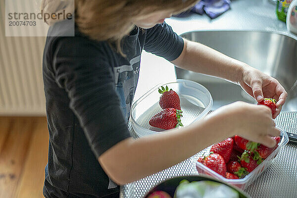 Kleiner Junge schneidet mit Hilfe seiner Mutter gesunde Erdbeeren