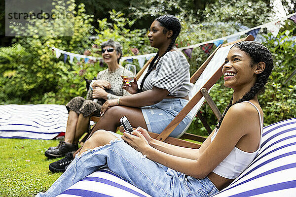 Eine gemischte Gruppe aus Freundinnen und Familienangehörigen trifft sich  um Spaß zu haben und eine sommerliche Grillparty im Garten zu genießen.