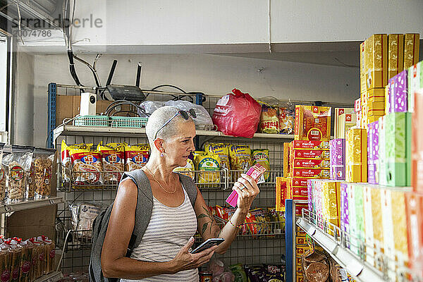 Alleinreisende Frau mittleren Alters in einem örtlichen Geschäft im Norden Thailands.