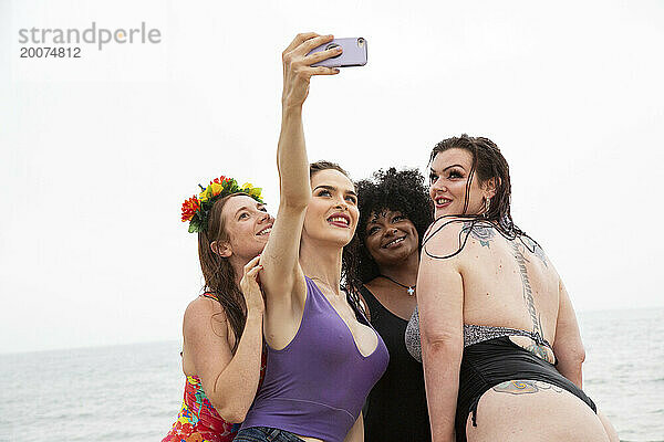 Gemischte Gruppe von Freundinnen  die Spaß am Strand haben und Selfies machen.