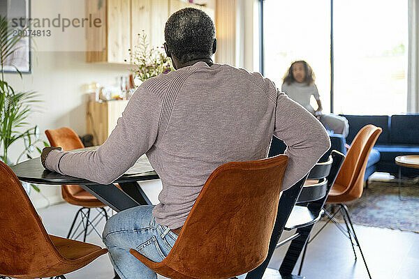 Eltern gemischter Abstammung sitzen am Küchentisch und diskutieren über das Leben  Rechnungen und die Organisation des Familienlebens. Entspannen Sie sich bei einer Tasse Kaffee