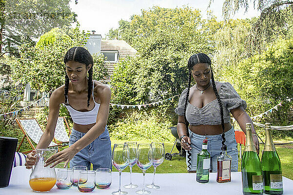 Zwei junge schwarze Schwestern bereiten den Getränketisch für eine Gartenparty im Freien vor