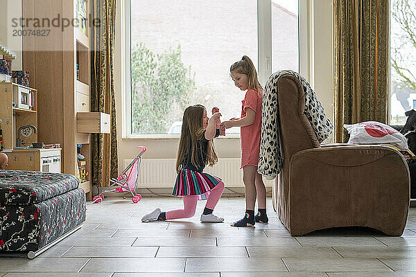 Zwei Schwestern spielen herum und haben gemeinsam Spaß in ihrem Wohnzimmer
