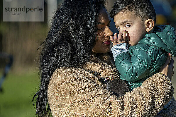 Mutter und Sohn umarmen sich im Park.