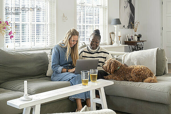 Freunde sitzen zusammen mit ihrem Laptop auf dem Sofa und planen einen Urlaub