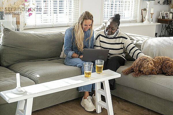 Freunde sitzen zusammen mit ihrem Laptop auf dem Sofa und planen einen Urlaub