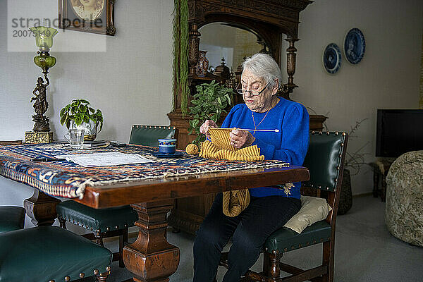 Ältere Dame strickt an ihrem Esstisch