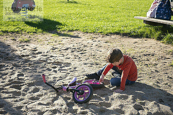 Kleiner Junge spielt in Frieden in einer Sandgrube in einem örtlichen öffentlichen Park