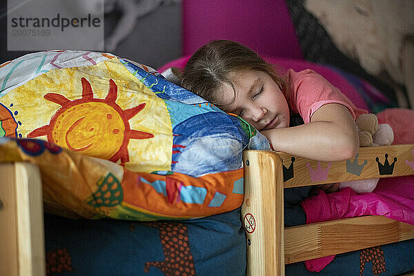 Junges Mädchen schläft friedlich auf ihrem Bett  umgeben von Teddys