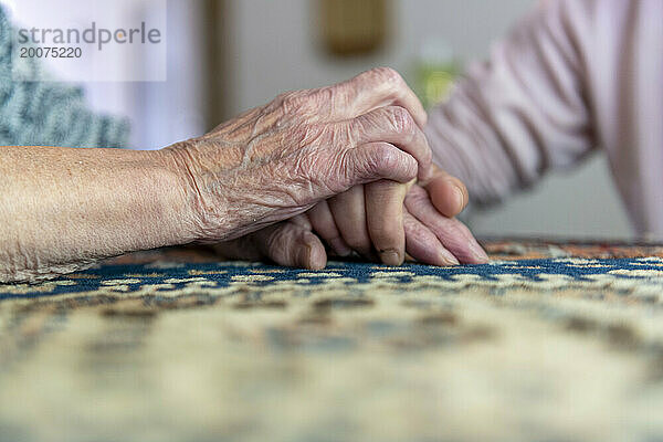 Ältere Frau hält ihre Tochter liebevoll an der Hand
