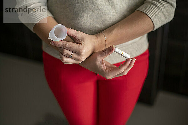 Woman holding her monthly menstruation health products  cup and tampon