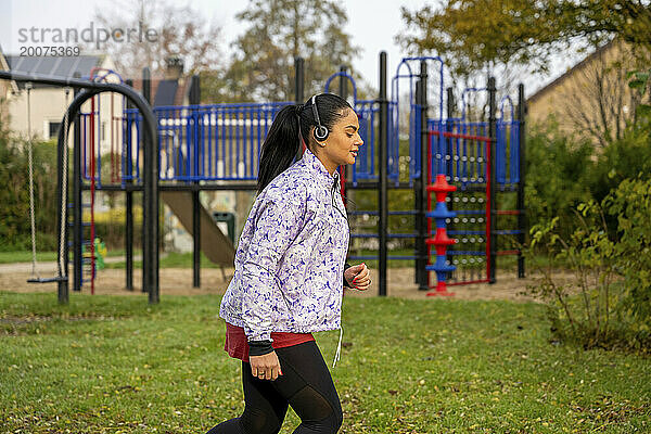 Gesunde Frau joggt und hört Musik im öffentlichen Park