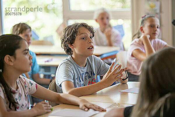 Kleiner Junge in der Klasse beantwortet die Fragen der Lehrer