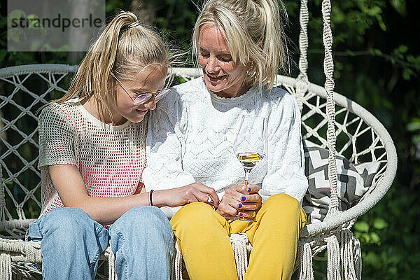 Mutter und Tochter vertrauen sich an  plaudern  verbinden sich bei einem Glas Wein in der Sonne