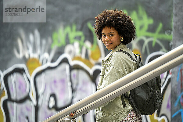Trendige junge Afrikanerin gemischter Abstammung  die glücklich durch die Stadt läuft.