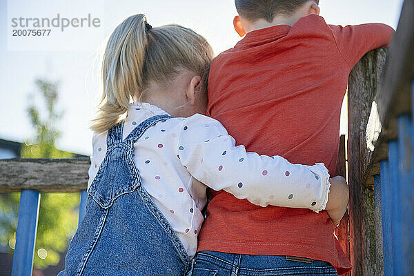 Bruder und Schwester umarmen sich und freunden sich in einem öffentlichen Park an. Schwester umarmt ihren Bruder