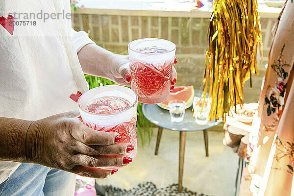 Zwei Freunde sitzen in der Sommersonne auf ihrem Balkon und essen ein gesundes Mittagessen mit Cocktails