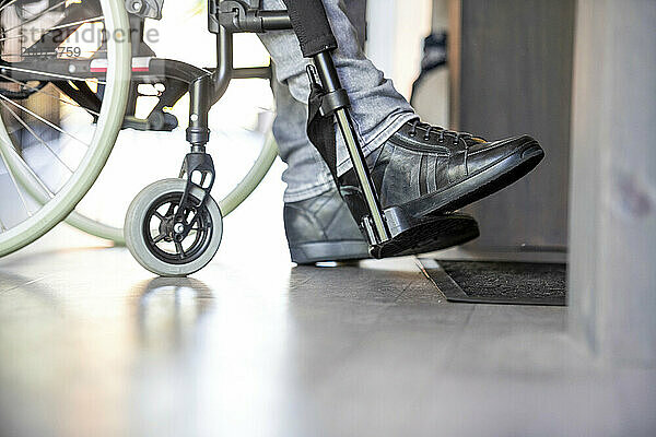 Mann im Rollstuhl bereitet sich darauf vor  seine Schuhe anzuziehen