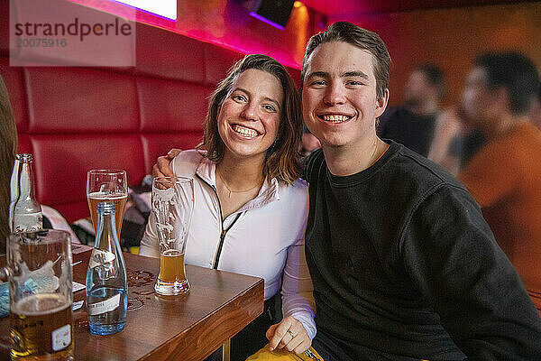 Junge Freunde feiern in einer Bar und haben Spaß beim Lachen und Herumspielen.