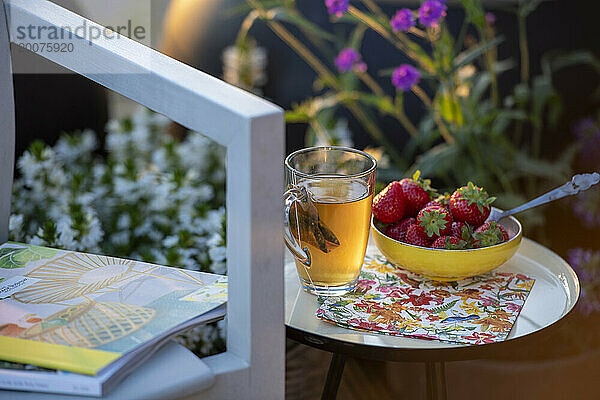 Beakfast of tea and strawberries on a beautiful table in the summer sunshine.