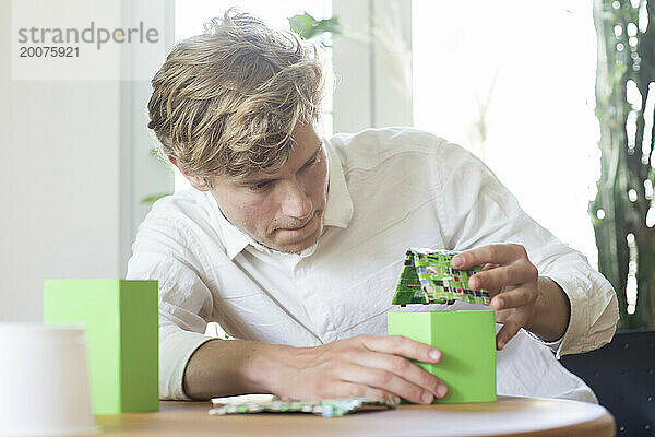 Junger Mann baut ein Hausmodell mit grüner Energie