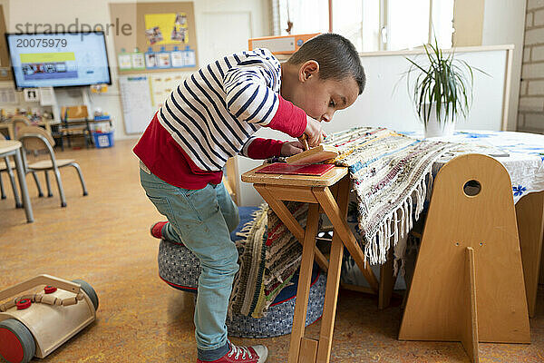 Kleiner Junge übt Bügeln am Vorschultisch und erledigt Hausarbeit