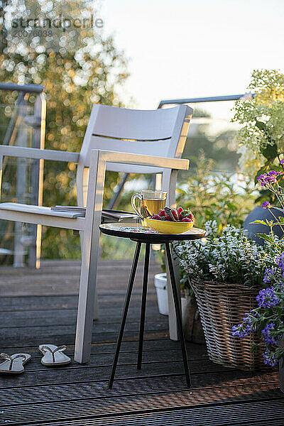 Frühstück mit Tee und Erdbeeren auf einem schönen Tisch in der Sommersonne.