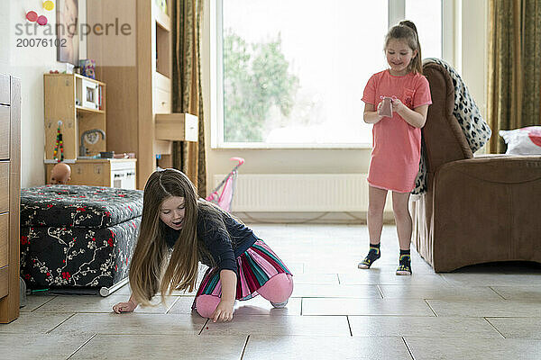 Junge Schwestern spielen in ihrem Wohnzimmer und haben Spaß daran  Kontakte zu knüpfen