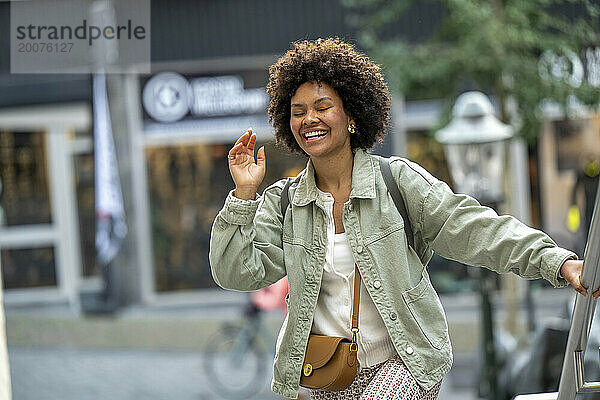 Trendige junge Afrikanerin gemischter Abstammung  die glücklich durch die Stadt läuft.