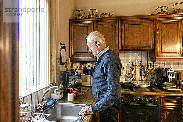 Älterer Mann bereitet Mittagessen zu und bereitet eine Tasse Tee zu