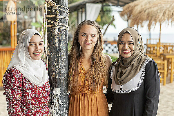 Porträt von drei Freundinnen  zwei davon tragen Hijab  in einer Küstenstadt im Süden Thailands.