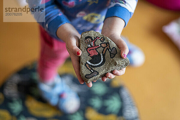 Young girl showing her amazing artwork painting on a rock of a dancing figure