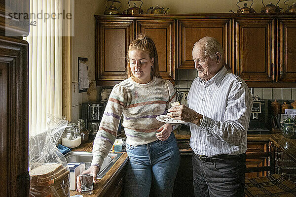 Älterer Mann mit betreuter Wohnfrau  die das Frühstück organisiert