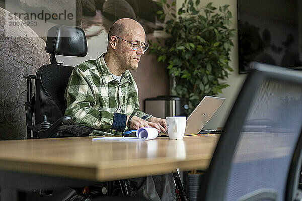 Behinderter Geschäftsmann  der an seinem Computer arbeitet.